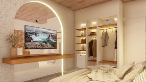 A bedroom with a TV mounted on a wooden shelf, a wardrobe with shelves, and a bed with a blanket. - Moã Charme Hotel (Mucuge)