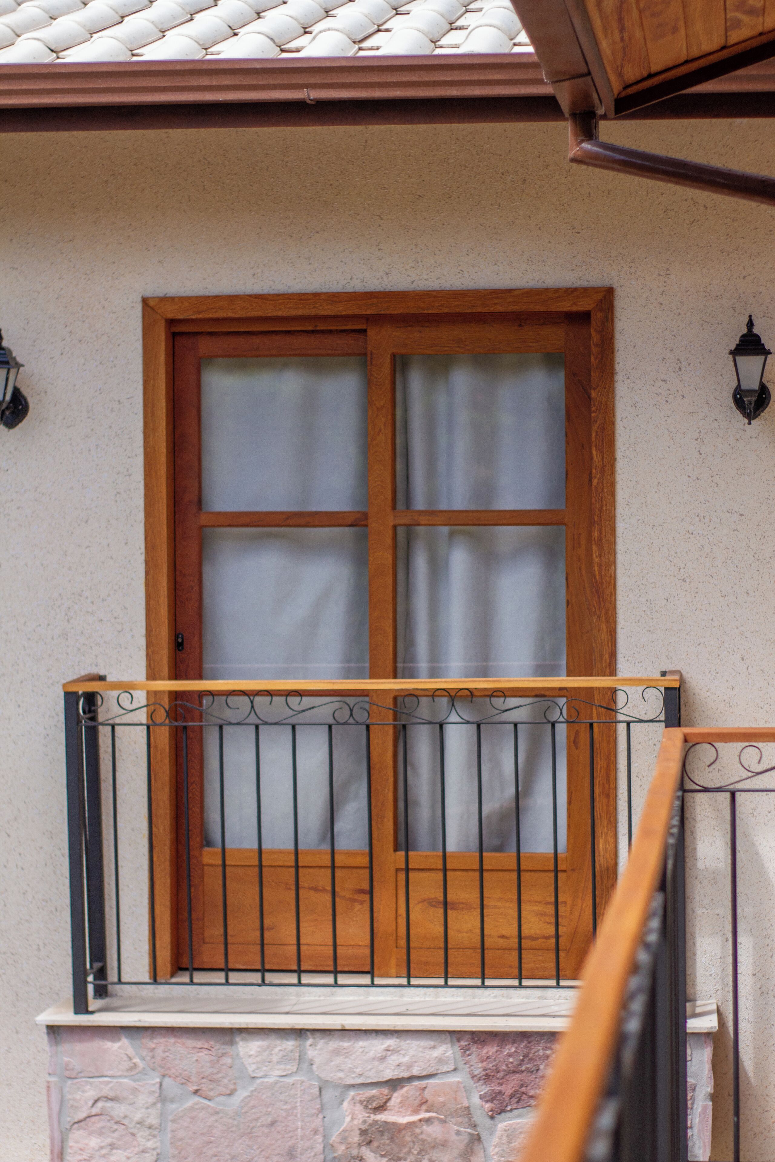 Ventana con marco de madera y barandilla de balcón de metal.