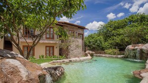 A two-story building with a pool, surrounded by greenery and a clear sky. - Moã Charme Hotel (Mucuge)