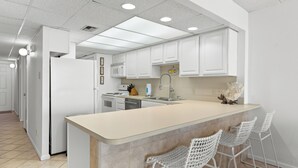 Una cucina moderna con mobili bianchi, un'isola centrale con sgabelli da bar e illuminazione a incasso.