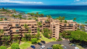 A multi-story hotel with a central courtyard surrounded by lush greenery and palm trees. - Oceanview Kahana Villa - Walk to Beach & Dining (Lahaina)