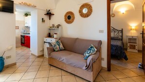 Un salon confortable avec un canapé, un téléviseur et une cuisine en arrière-plan.