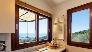 Une cuisine avec vue sur la mer, une fenêtre avec un cadre en bois et un porte-serviettes.