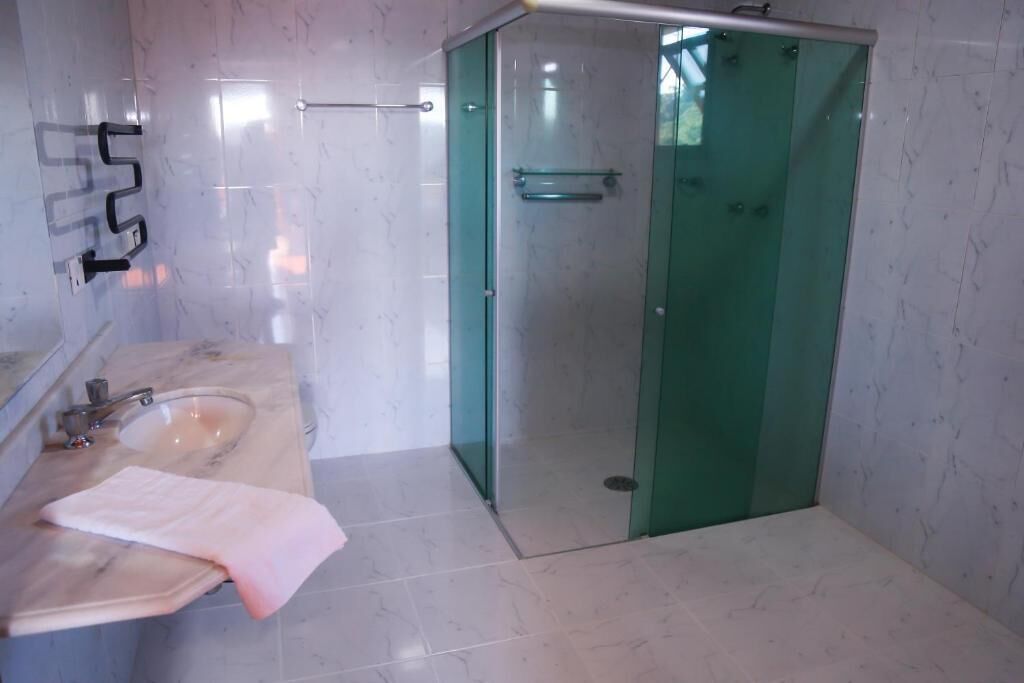 A bathroom with a marble sink, a glass shower enclosure, and a towel on the counter.
