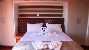 A hotel room with a large bed, a headboard with horizontal slats, and a wardrobe with two doors. - Pousada DonaBella (Campos do Jordão)