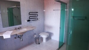 A bathroom with a sink, toilet, and glass shower enclosure. - Pousada DonaBella (Campos do Jordão)