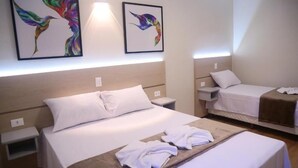 A hotel room with two beds, a headboard, bedside tables, and artwork on the wall. - Pousada DonaBella (Campos do Jordão)
