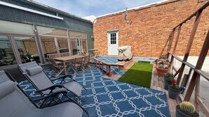 Een terras met lounge fauteuils, een tafel en een zwembad.