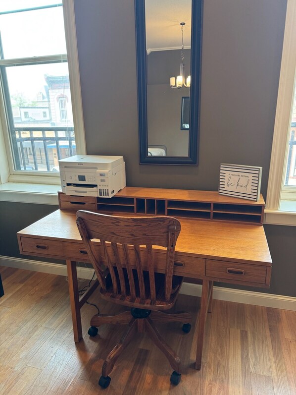 A wooden desk with a chair, a printer, and a framed inspirational quote.