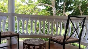 A covered outdoor seating area with wicker furniture and a white decorative railing. - exotic beach & villa with WiFi, AC in tranquil Tower Isle with pool (Tower Isle)
