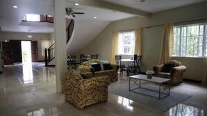 A spacious living area with a high ceiling, a staircase, and a large window with curtains. - exotic beach & villa with WiFi, AC in tranquil Tower Isle with pool (Tower Isle)