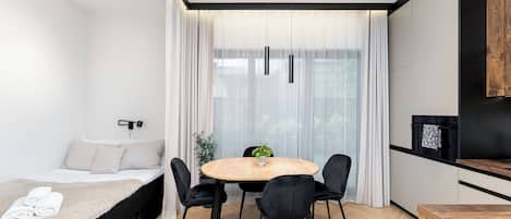 A modern bedroom with a bed, bedside table, and a window with sheer curtains.