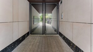 Un corridoio con un cancello metallico chiuso, pareti e pavimento piastrellati.
