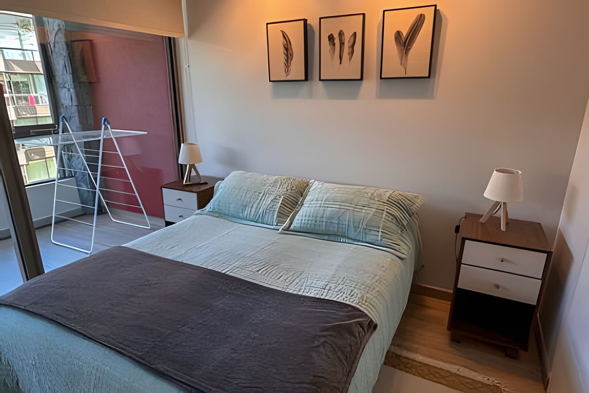 A bedroom with a bed, two bedside tables, a nightstand, a window, and a door.