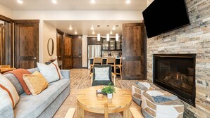 A modern living room with a fireplace, a dining area, and a kitchen in the background. - Steps to Cabriolet | Pool, Spa at Blackstone - Canyons Village Fun (Park City)