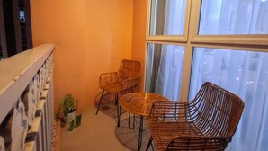 Un balcón con dos sillones de mimbre y una pequeña planta en maceta.