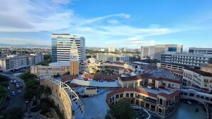 Un paisaje urbano que combina arquitectura moderna e histórica, incluyendo un edificio destacado con un campanario verde y una edificación tradicional con cúpula.