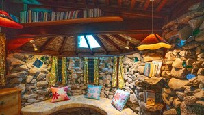 Un rincón acogedor para leer con pared de piedra, un banco de madera y varios cojines.