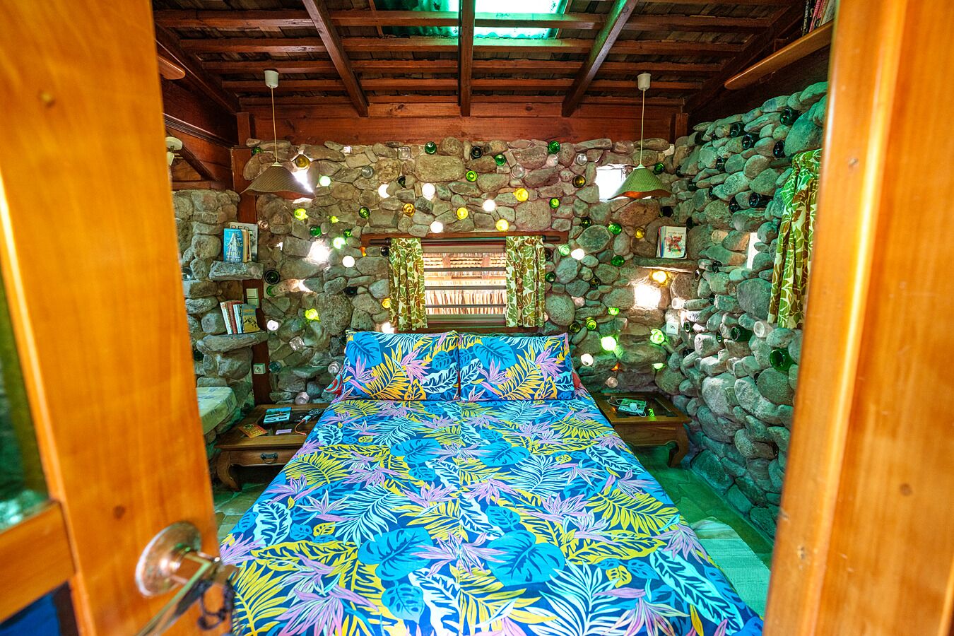 A room with a bed, stone walls, and hanging lights.