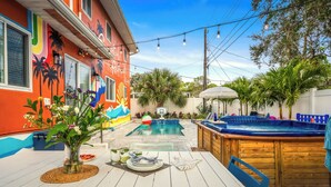 Ein Garten mit Pool, Whirlpool und Essbereich, gedeckt für zwei Personen.