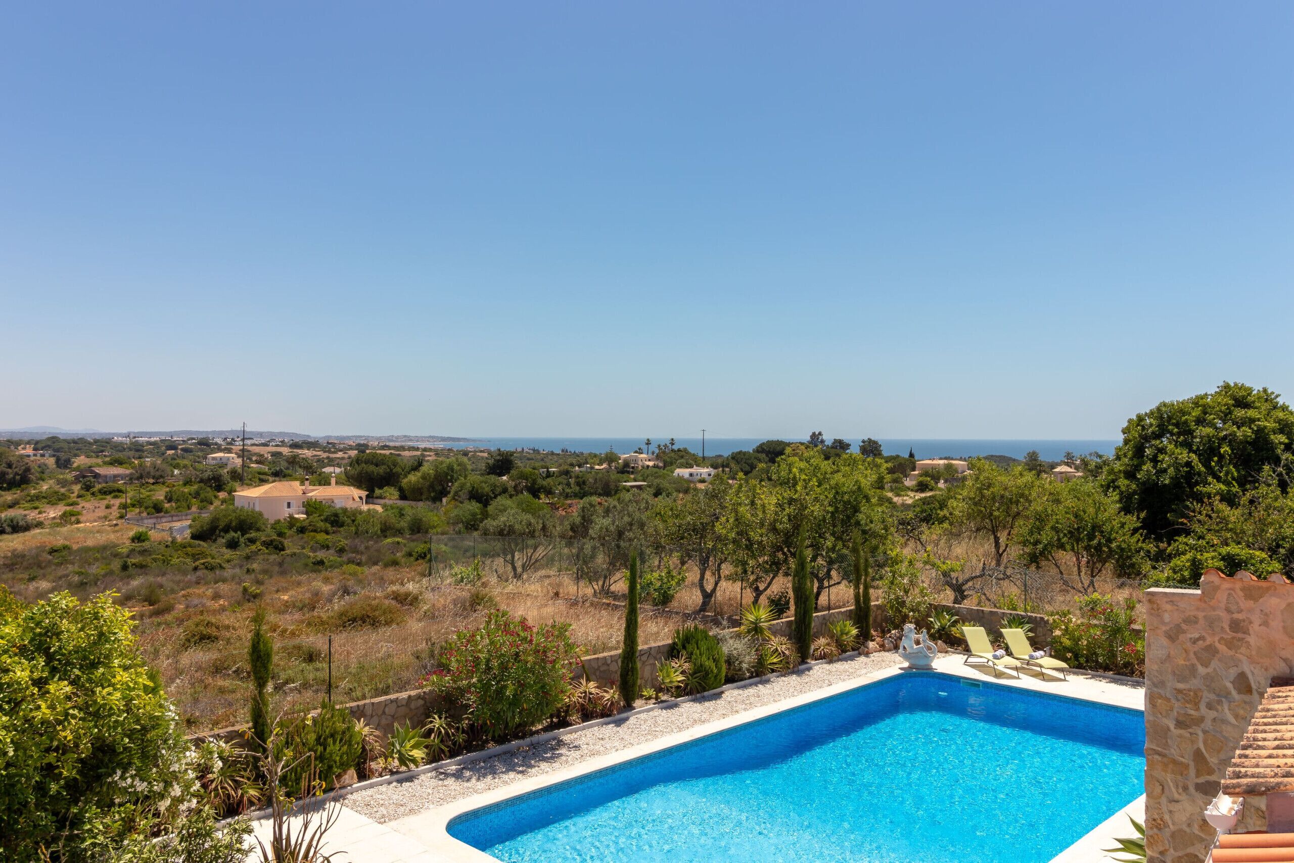 Piscina com vista desobstruída da paisagem ao redor, incluindo árvores e edifícios distantes.