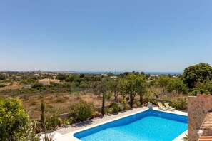 A swimming pool with a clear view of the surrounding landscape, including trees and distant buildings.