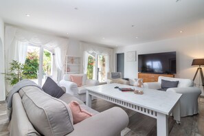 A modern living room with a white sofa, a coffee table, and a TV.