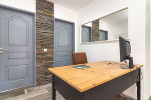 Una habitación con un escritorio de madera, un monitor de computadora y un espejo en la pared.