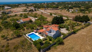 Una propiedad residencial con piscina, rodeada por un patio cercado y vista al mar.