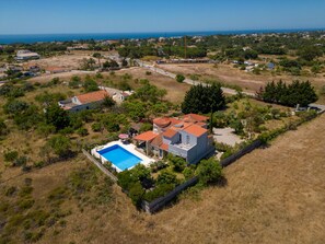 Une propriété résidentielle dotée d’une piscine, entourée d’une cour clôturée et offrant une vue sur la mer.