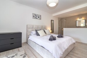 Un dormitorio moderno con una cama grande, una mesita de noche, un aparador y un espejo.