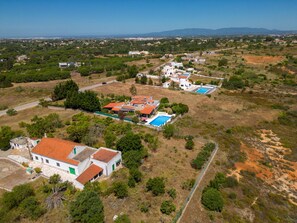 Vista aérea de una zona residencial con varias casas, una piscina y un paisaje verde.