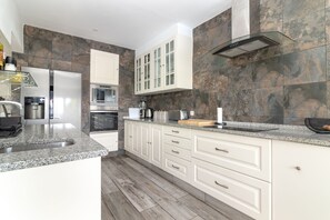 A modern kitchen with granite countertops, white cabinetry, and a stone backsplash. - Quinta Delsy - 5 Bed Villa With Pool Near Praia da Marinha (Lagoa)
