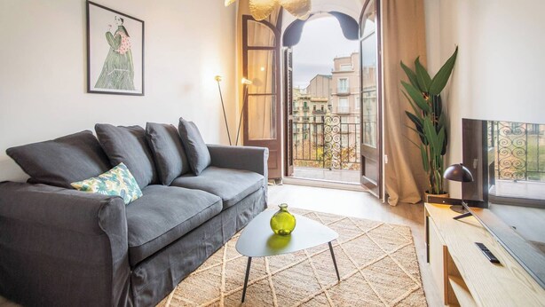 En moderne stue med en grå sofa, et lille hvidt sofabord og en grøn vase.
