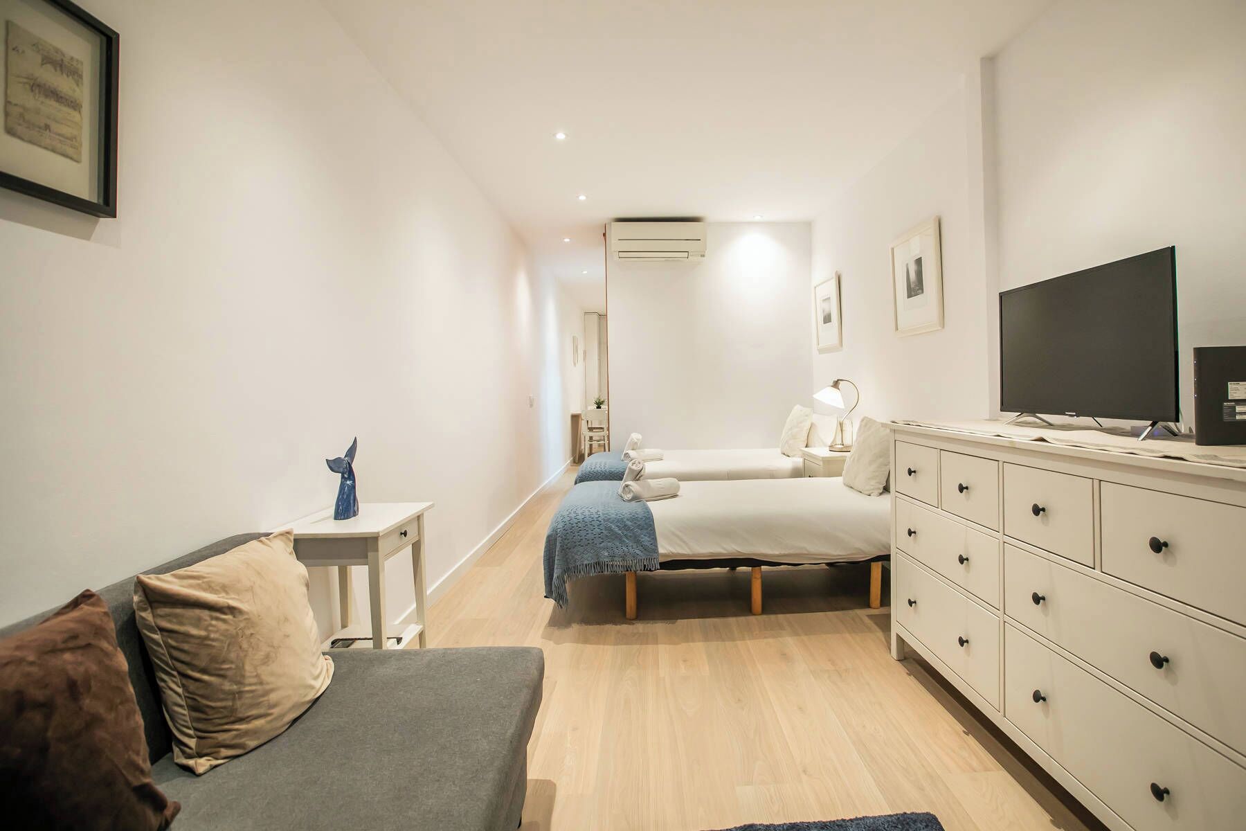 Een moderne hotelkamer met een bed, een televisie, een dressoir en een klein bureau met stoel.