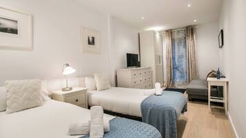 Een hotelkamer met twee bedden, een kaptafel, een televisie en een bureau met stoel.