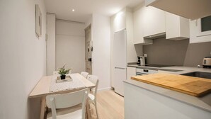 Eine kleine Küche mit weißen Schränken, einer Holzauskładung und einem Essbereich mit Tisch und Stühlen.