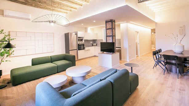 Un salon moderne avec un canapé vert, une table basse blanche et un téléviseur à écran plat.