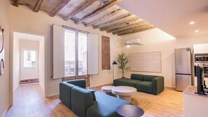 Un salon moderne avec un canapé vert, une table basse blanche et un coin repas comprenant un réfrigérateur et un four.