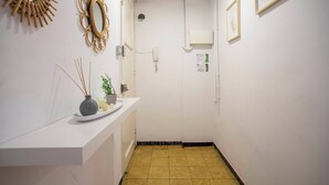 Um corredor com uma receção branca, um espelho e quadros nas paredes.