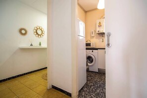 Un cuarto de lavado con lavadora, secadora y un pequeño estante con objetos decorativos.