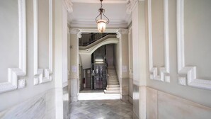 Um corredor com chão de mármore e escadaria que leva a um andar superior.