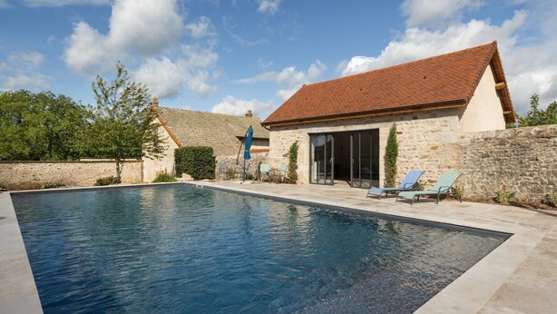 A swimming pool with a stone wall and a building with a tiled roof. - La Maison de Marius - SAINT BONNET DE JOUX (SAINT BONNET DE JOUX)