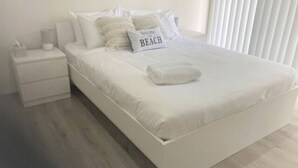 A neatly made bed with a pillow that reads "Welcome to Beach." - Shellharbour Beach Daze (Shellharbour)
