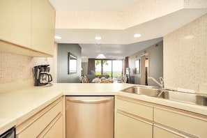 Kitchen features a central island with sink and dishwasher, light-colored cabinetry, and a large countertop.