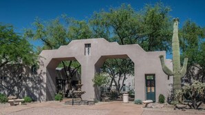 Un edificio con un diseño arquitectónico único, que incluye una gran entrada en arco y un cactus al frente.