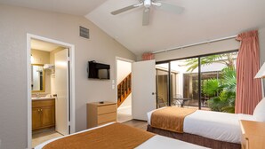 A hotel room with two beds, a TV, a bathroom with a mirror, and a view of the outdoors.