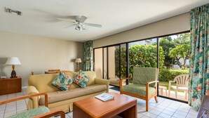 A living room with a sofa, two armchairs, a coffee table, and a ceiling fan.