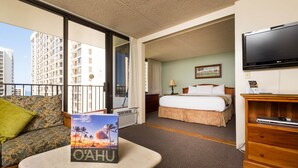 Une chambre d’hôtel avec un balcon, un lit, une télévision et une table avec un livre.