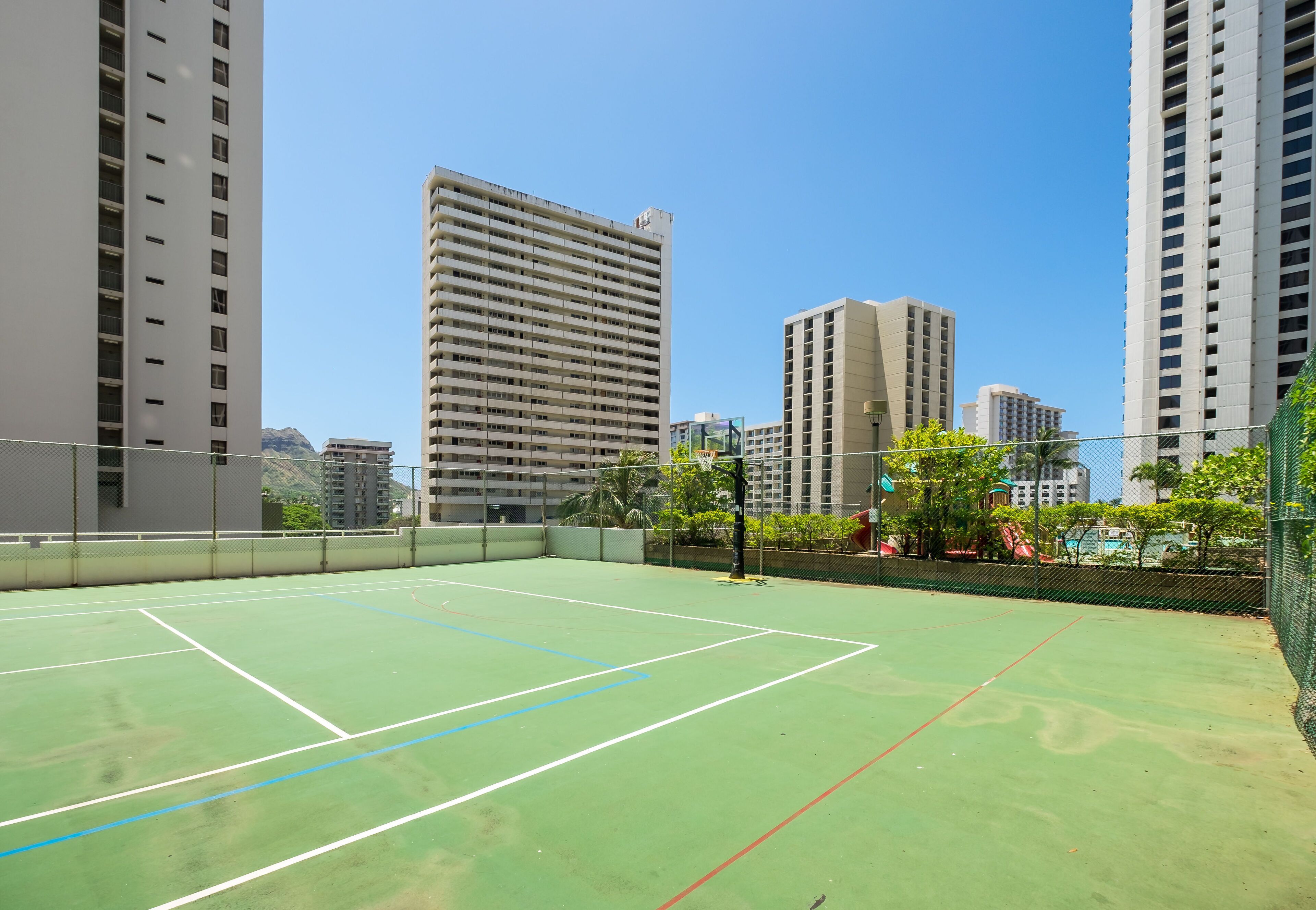 An outdoor tennis court surrounded by high-rise buildings.